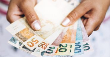 Mão segura dinheiro do pagamento do benefício emergencial